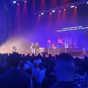 Band performing on a purple-lit stage for a standing audience in the Auditorium