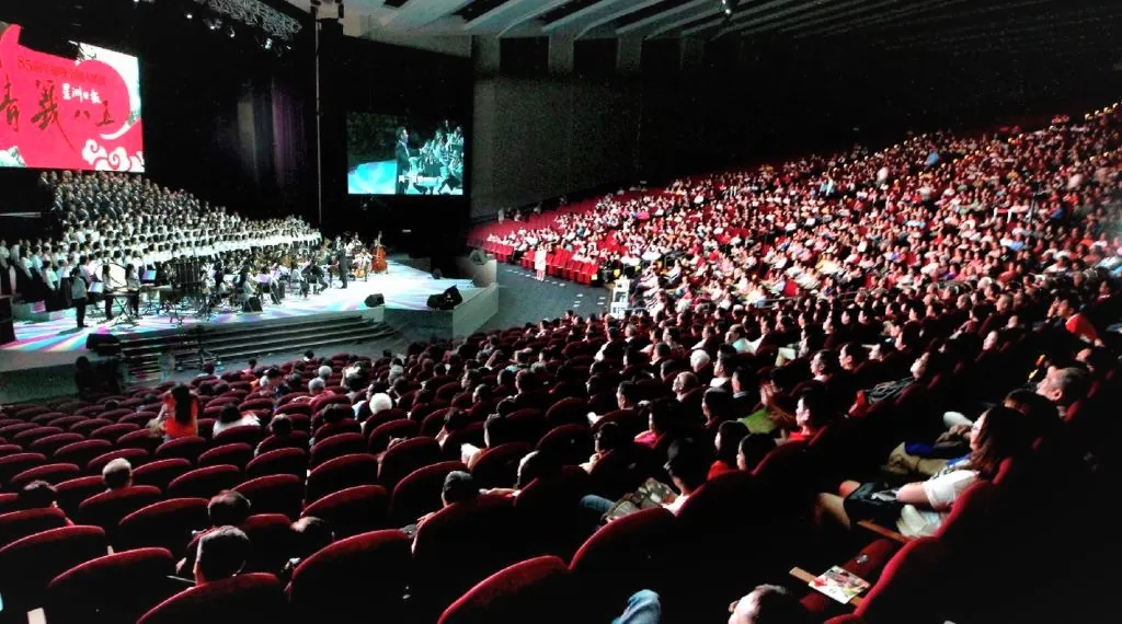 Audience in red seats watching a choir and orchestra concert in the Auditorium