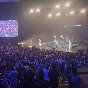 Standing concert crowd facing a lit stage and side screen in the Auditorium