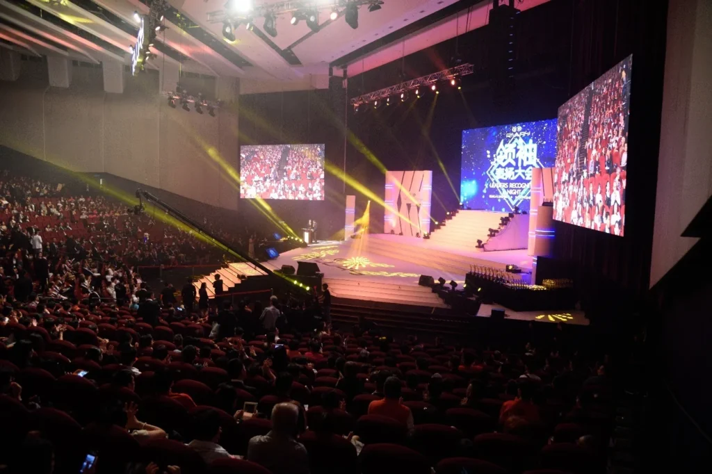 Side view of the Auditorium during a leaders' recognition night, with stage screens and a seated audience