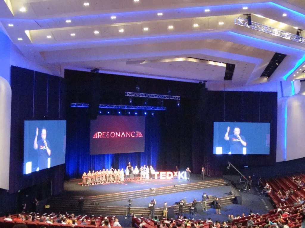 Choir performing on the TEDxKL stage in the Auditorium under the Resonance banner