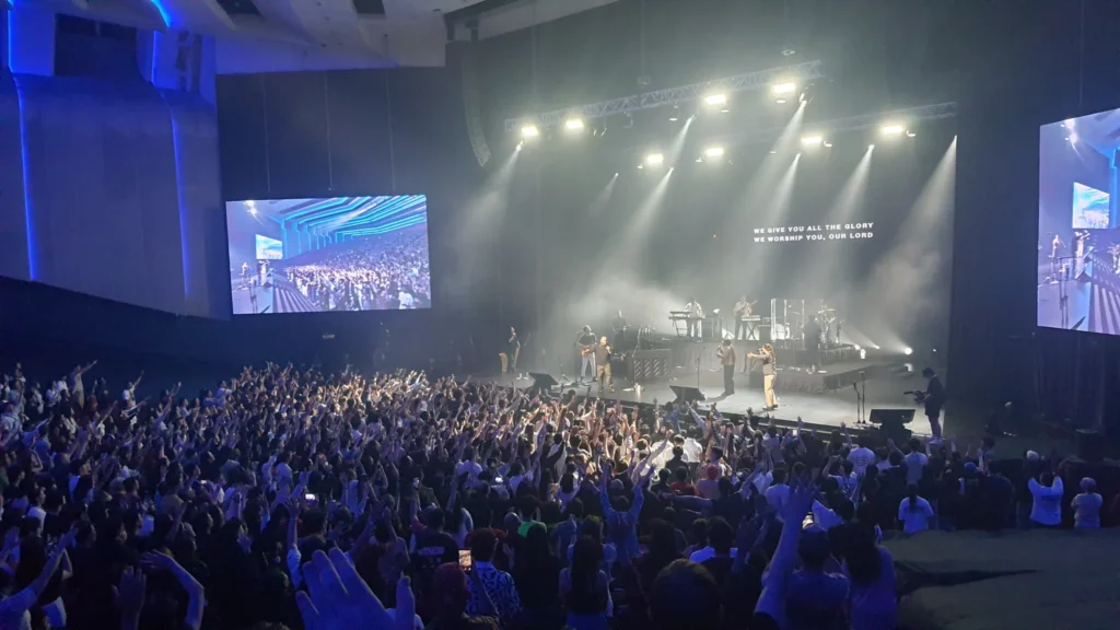 Band performing on the Auditorium stage between two LED screens as the audience raises their hands