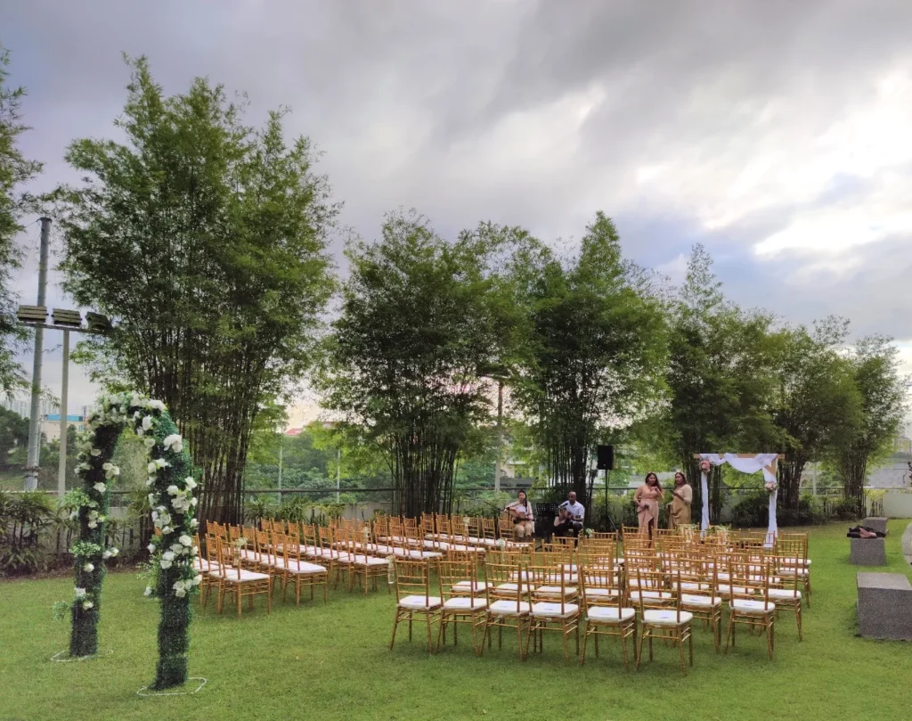 Floral arch and rows of gold chairs on the Garden lawn under a cloudy sky