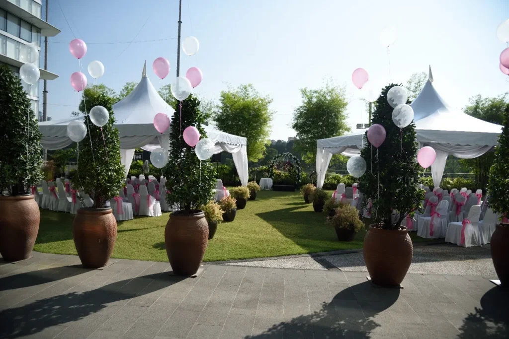 Pink and white balloons on potted trees along the path to a Garden wedding