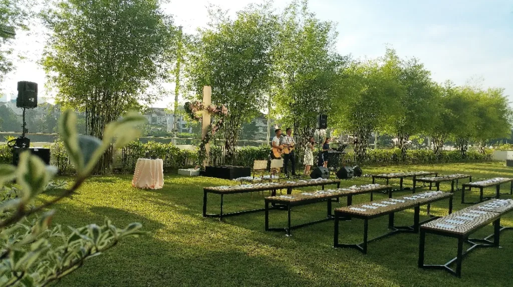 Wooden benches on the Garden lawn facing a band and a wedding cross