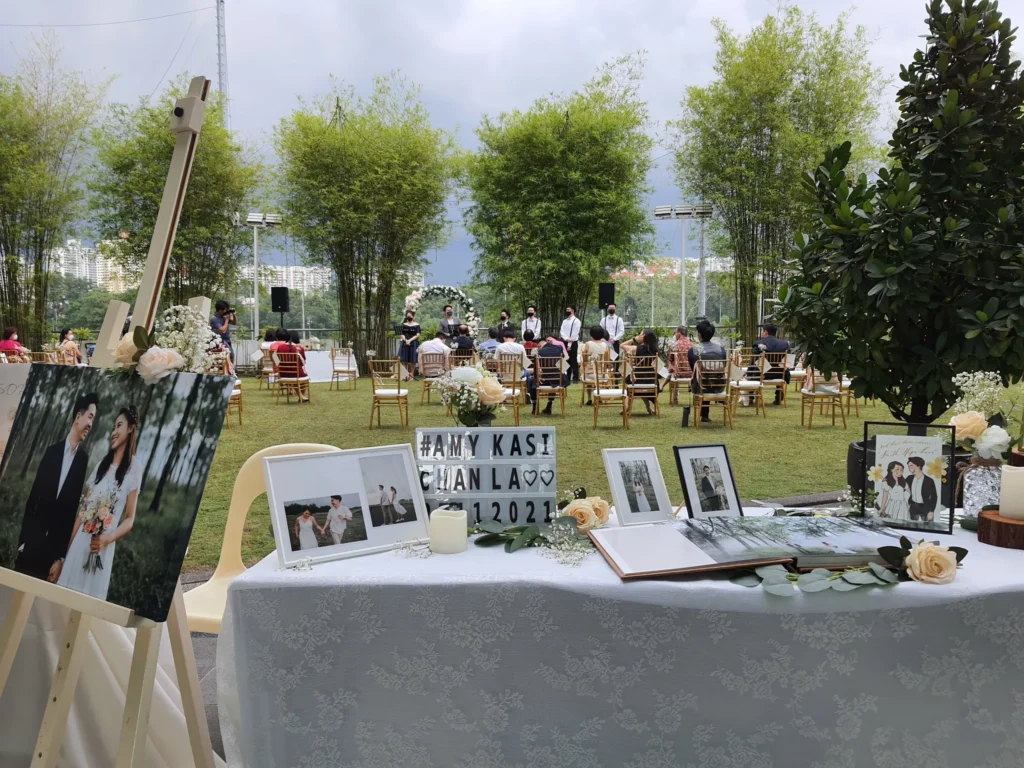 Table of framed couple photos and a guest book at a wedding in the Garden