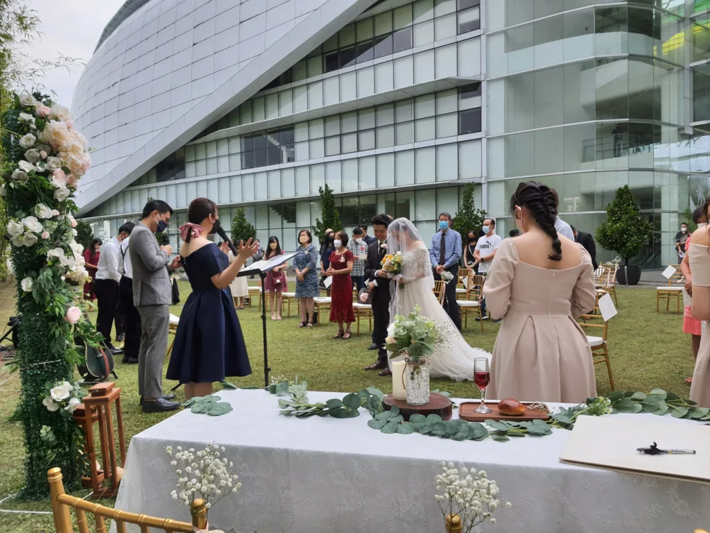 Wedding signing table with flowers as the couple and guests stand in the Garden