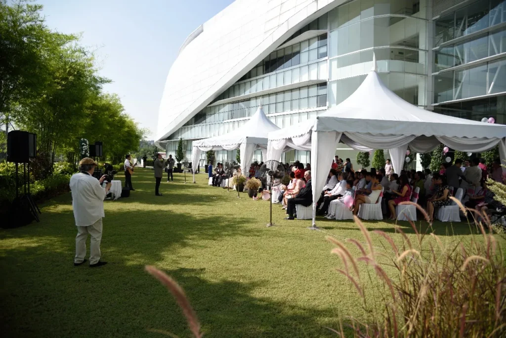 White tents with seated guests on the sunny Garden lawn beside the building