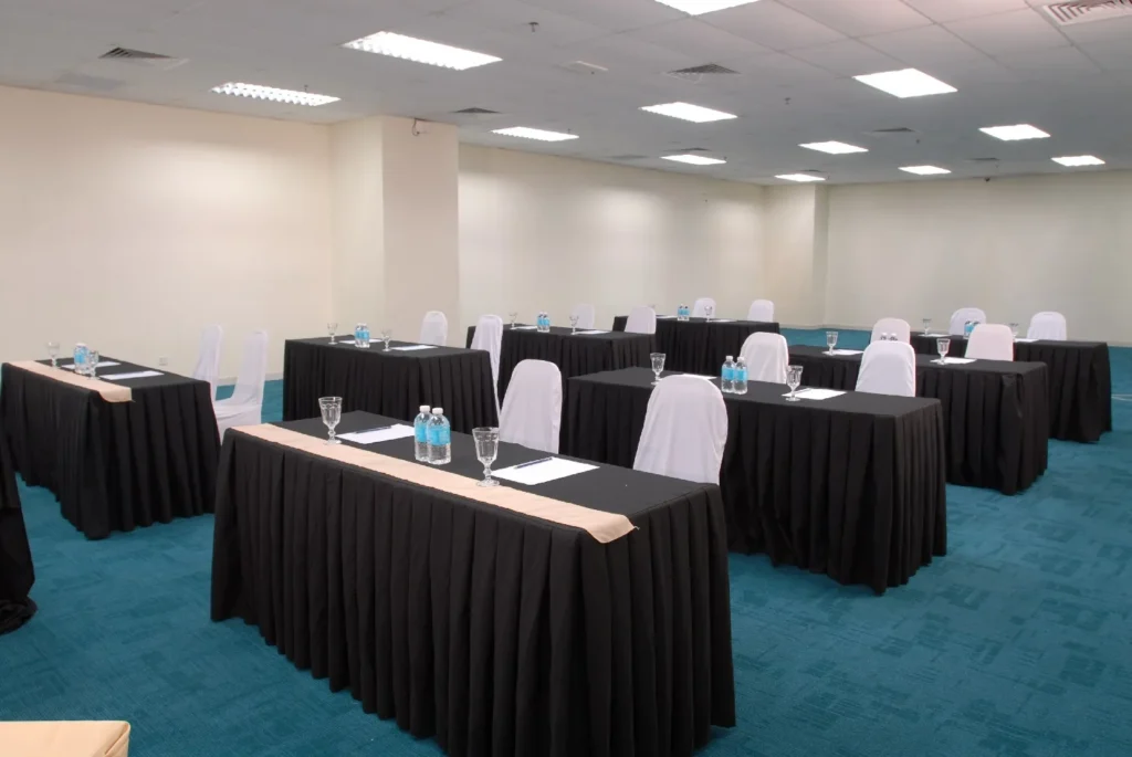 Classroom-style tables laid with water bottles and glasses in a meeting room