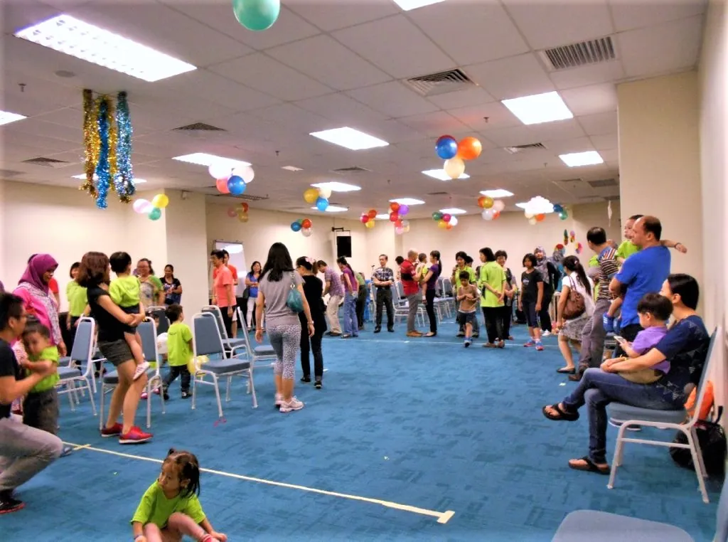 Families and children playing games in a meeting room decorated with balloons