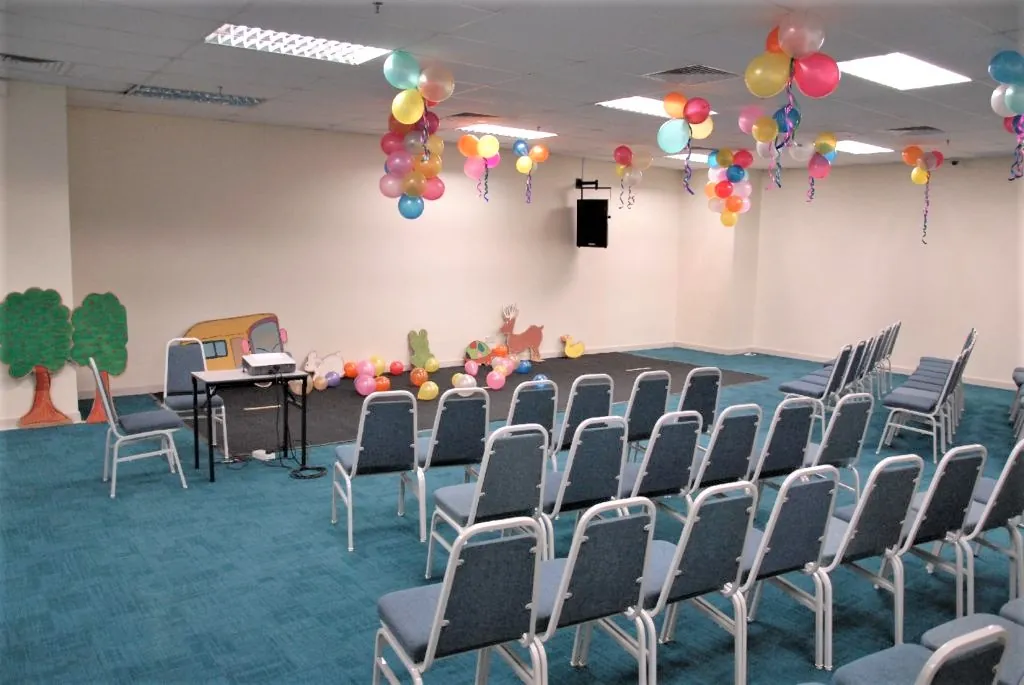 Chairs facing a painted kindergarten stage set in a meeting room