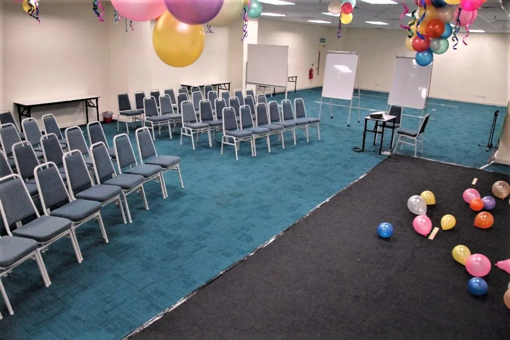 Black performance mat with balloons in front of rows of chairs in a meeting room