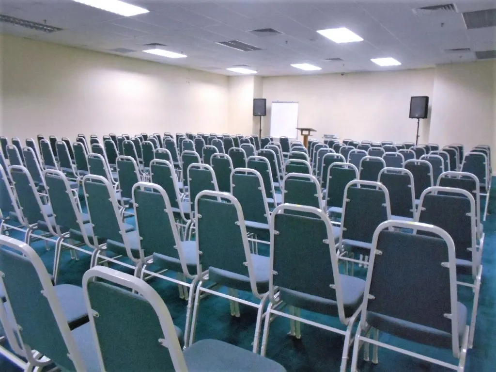 Rows of blue-grey chairs set up for a talk in a meeting room