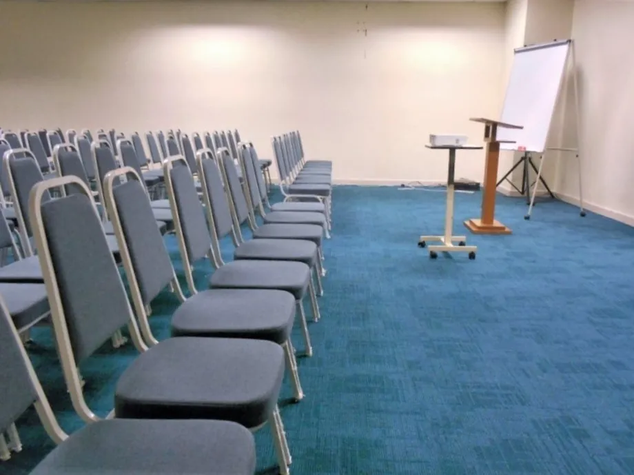 Lectern and flip chart beside rows of chairs set up for a talk in a meeting room