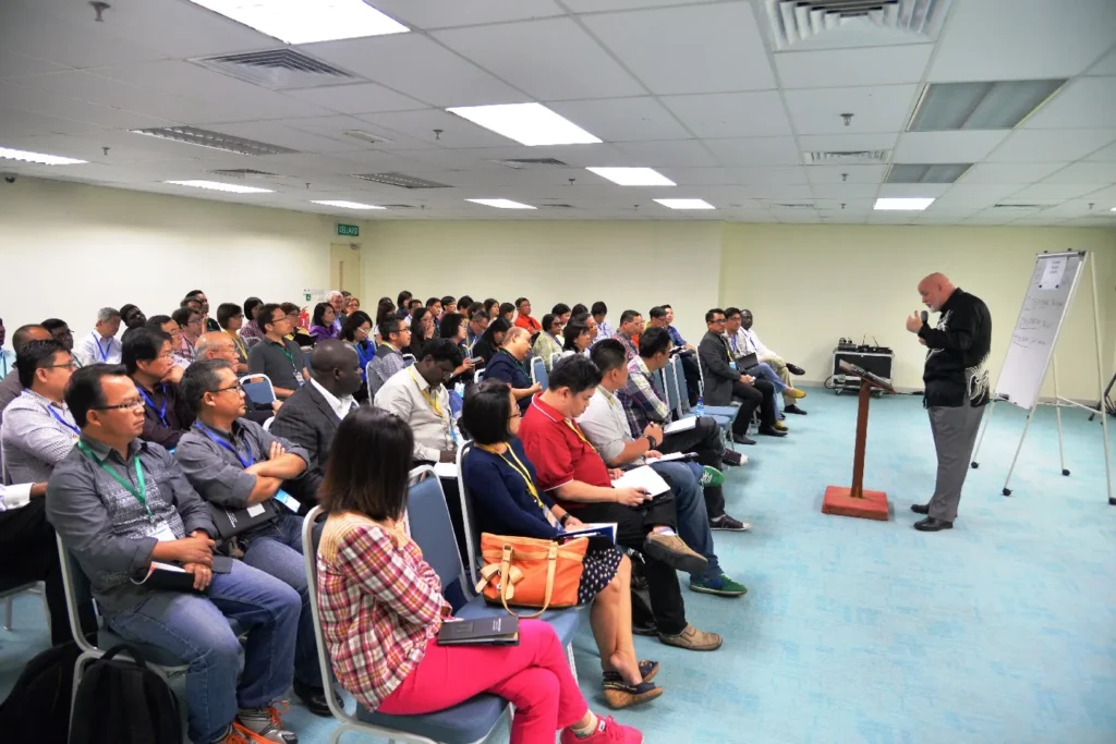Speaker at a lectern addressing a seated audience in a meeting room