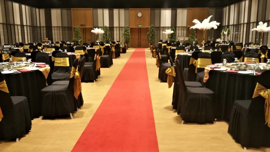 Wedding tables in black and gold on both sides of a red carpet in the Multipurpose Banquet Hall