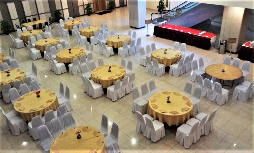 Round tables with gold cloths set out for an event buffet in the Multipurpose Banquet Hall lobby, seen from above