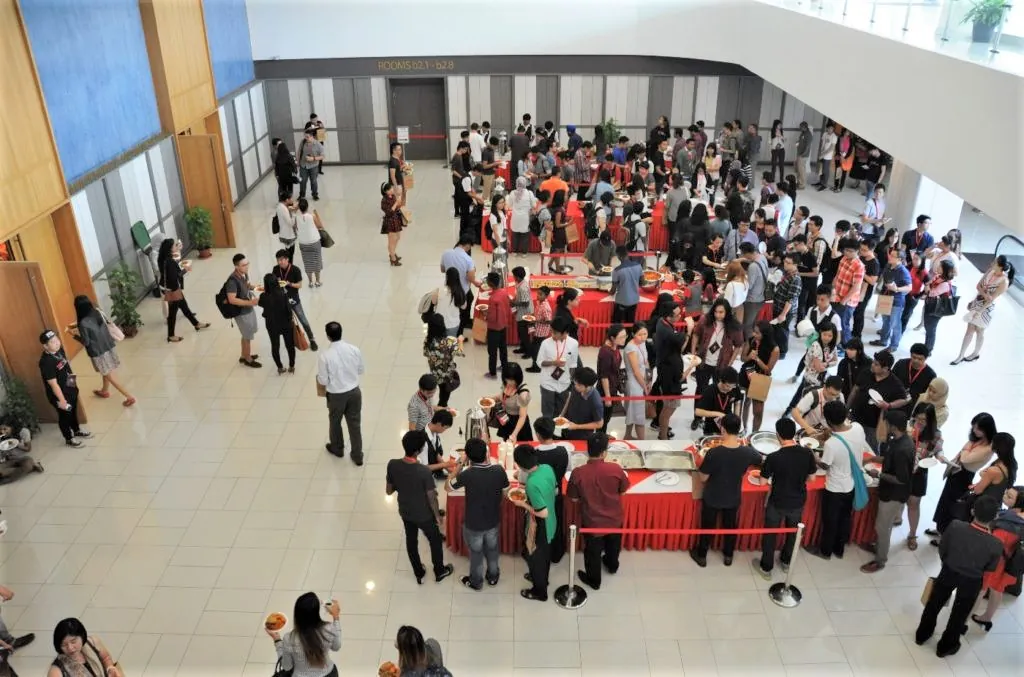 Guests queueing at a buffet line in the Multipurpose Banquet Hall lobby, seen from the level above