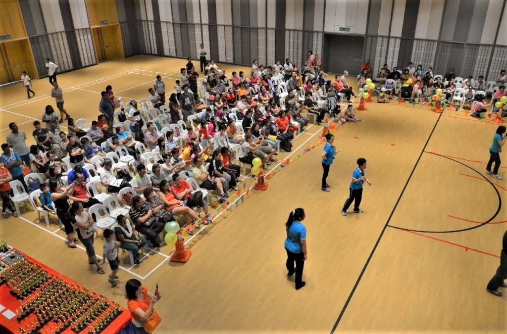 Parents seated around the floor watching a kindergarten sports day in the Multipurpose Banquet Hall