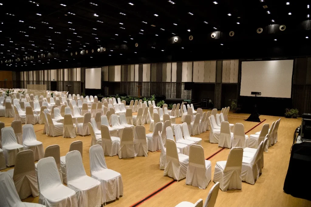 White-covered chairs in rows facing a projector screen in the Multipurpose Banquet Hall