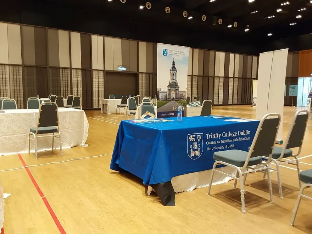 University exhibitor booth with a blue table at an education fair in the Multipurpose Banquet Hall