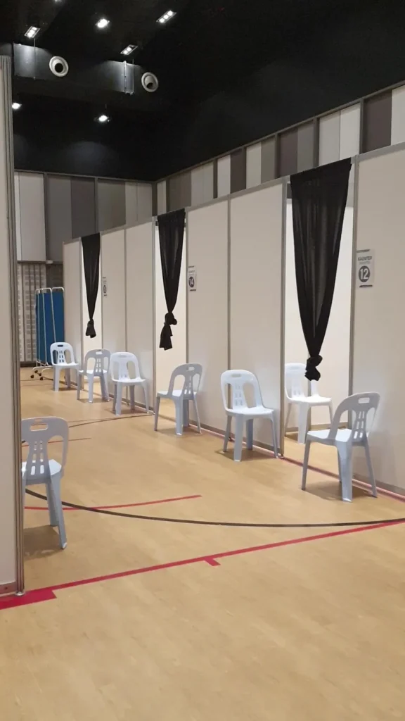 Numbered vaccination booths with curtains and waiting chairs set up in the Multipurpose Banquet Hall
