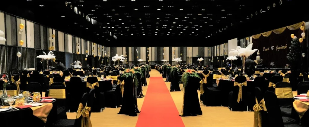 Red carpet aisle with feather centrepieces on black-draped wedding tables in the Multipurpose Banquet Hall