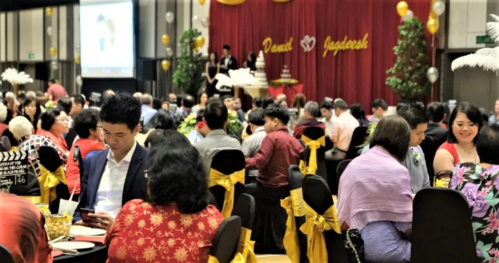 Wedding guests dining in front of a red stage backdrop in the Multipurpose Banquet Hall