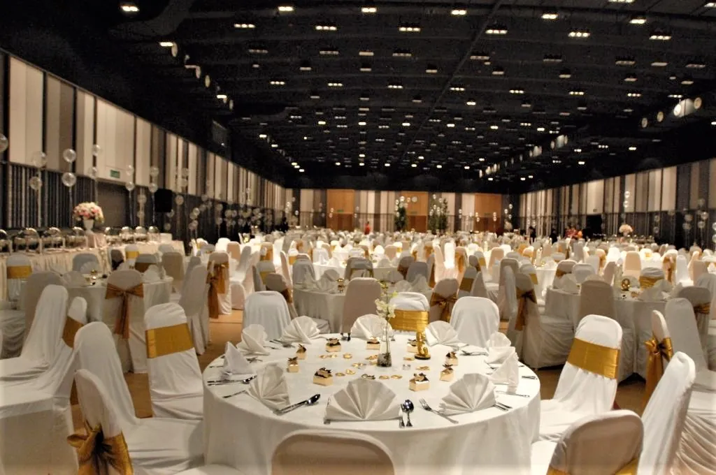 Wedding tables laid with napkins and gold chair sashes in the Multipurpose Banquet Hall