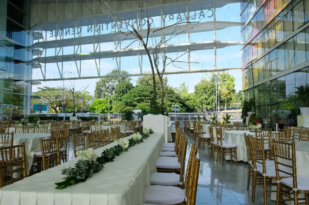 Long banquet tables with greenery runners and gold chairs in the Plaza