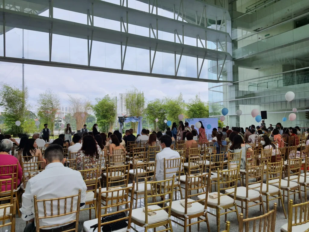 Large crowd seated in gold chairs at a wedding ceremony with balloons in the Plaza