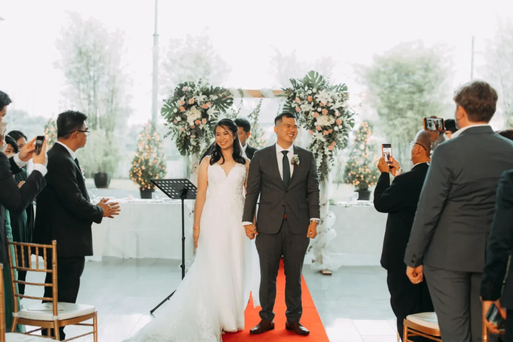 Newly married couple walking down the red carpet aisle in the Plaza as guests take photos