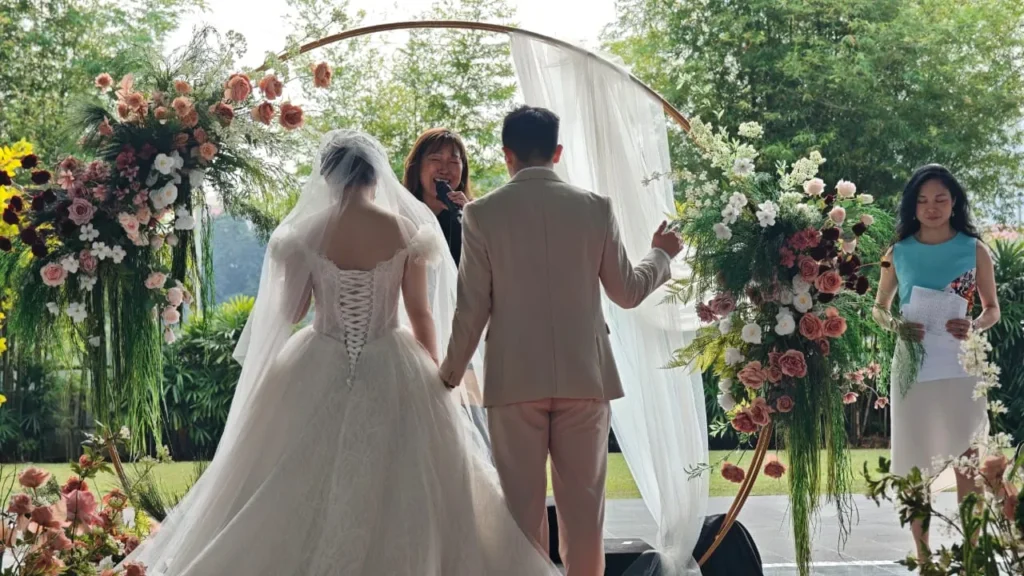 Bride and groom in front of a floral hoop arch with the officiant at a wedding in the Plaza