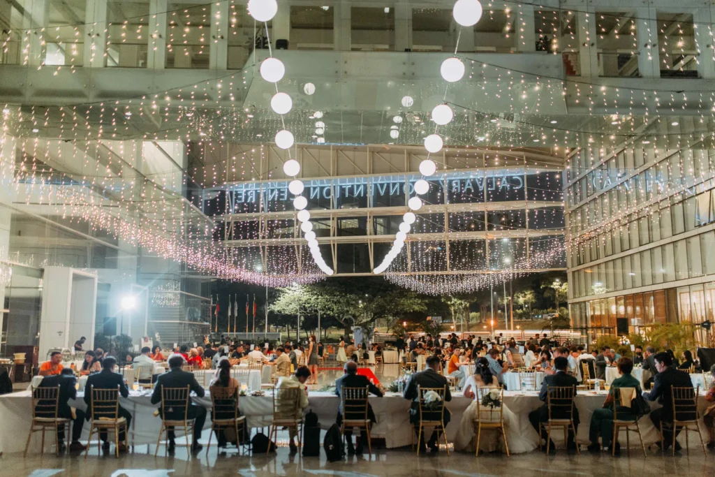 Wedding dinner in the Plaza at night under strings of fairy lights and hanging lanterns