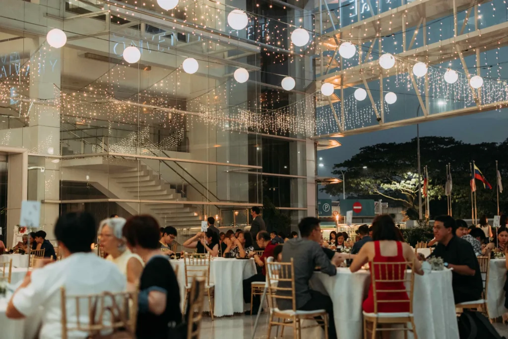 Wedding dinner under hanging lanterns and fairy lights in the Plaza at dusk