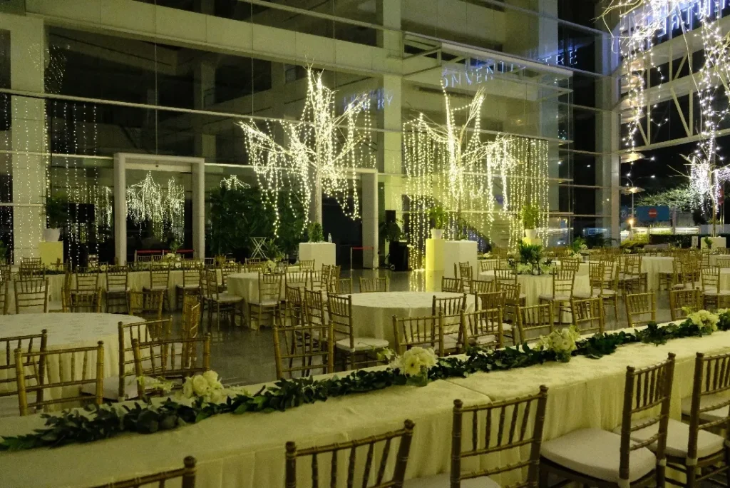 Wedding dinner tables among trees wrapped in fairy lights in the Plaza