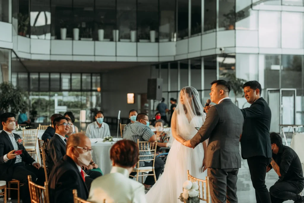 Groom saying his vows into a microphone, holding the veiled bride's hands, in the Plaza