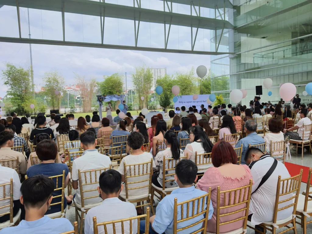 Guests on gold chairs among blue and pink balloons, facing a draped arch at a wedding in the Plaza
