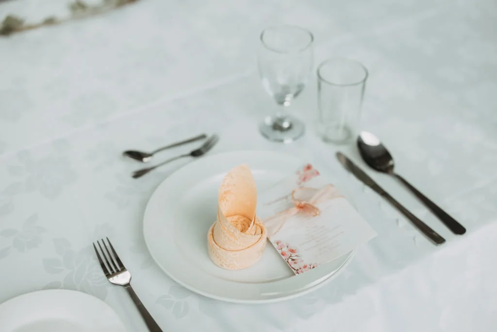 Wedding place setting with a folded napkin, cutlery and glasses on a white tablecloth in the Plaza