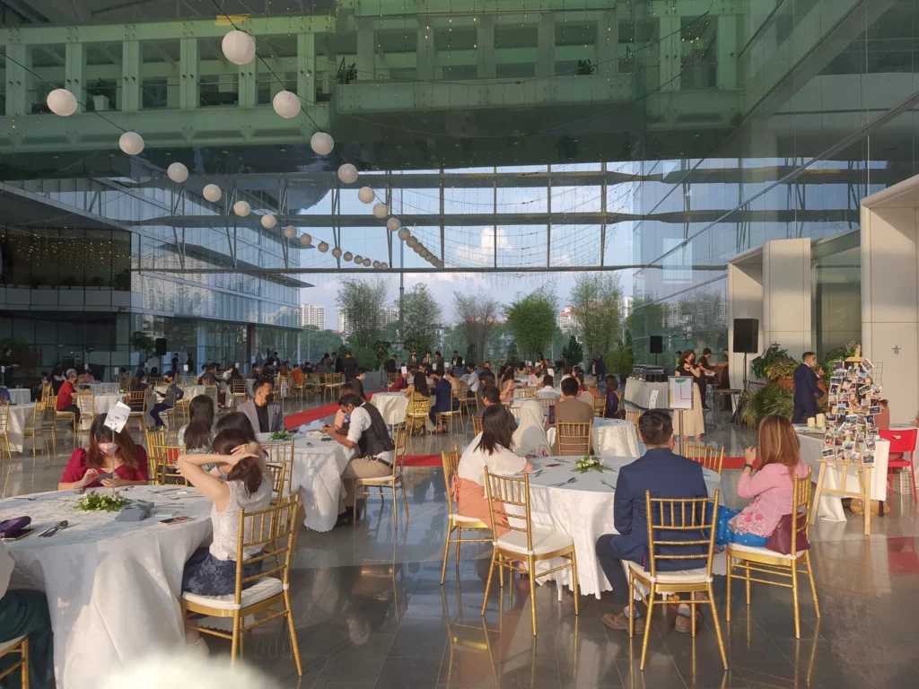 Guests at round tables with white cloths under hanging paper lanterns at a wedding reception in the Plaza