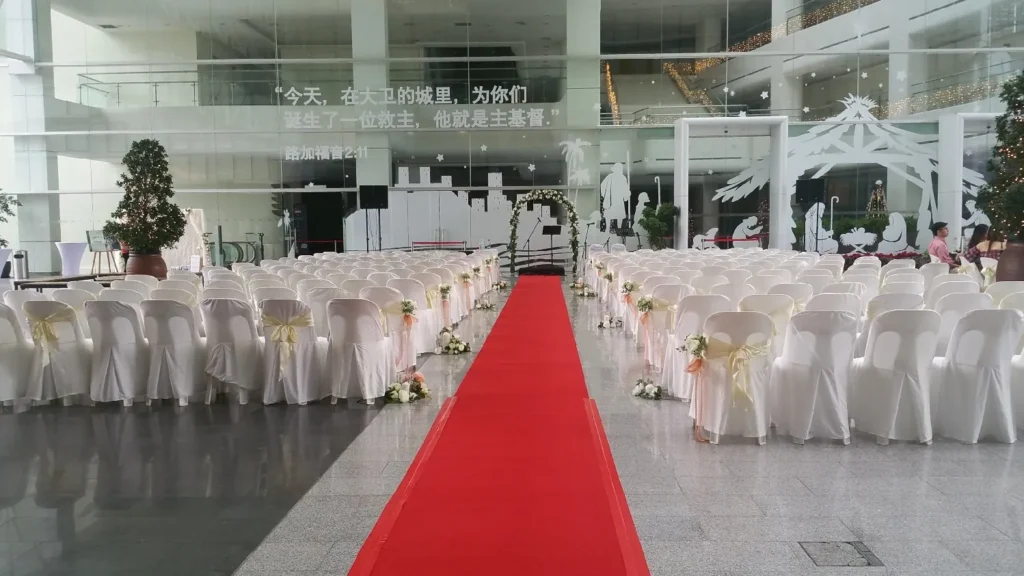 Red carpet aisle between rows of white chairs for a wedding in the Plaza
