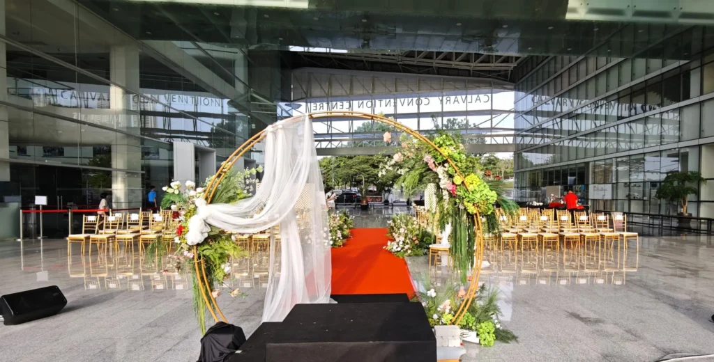 Round floral arch with white drapes at the end of a red carpet aisle, set up for a wedding in the Plaza