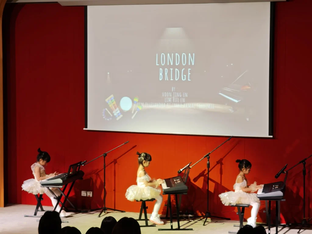 Three girls in tutus playing keyboards on a Theatrette stage