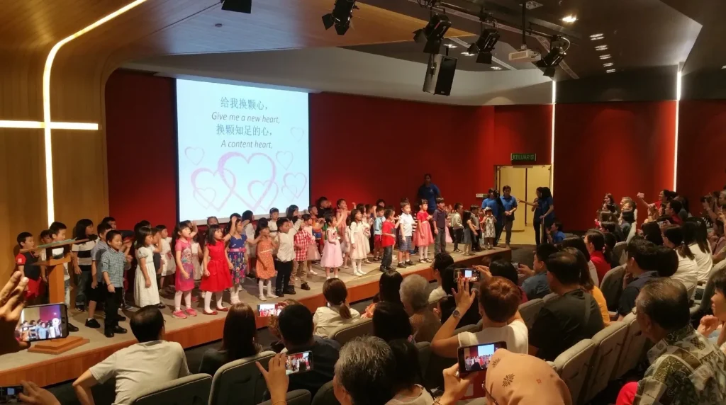 Children singing on a Theatrette stage as parents take photos