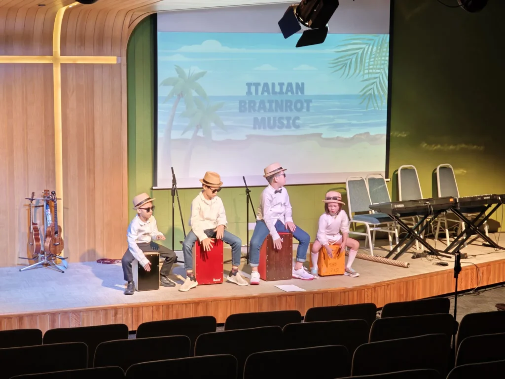 Children in hats playing box drums on a Theatrette stage