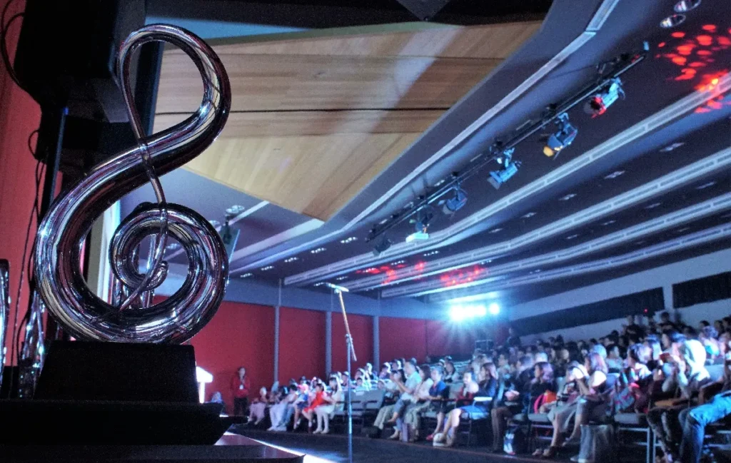 Full Theatrette audience at the Yamaha Electone Festival, with a treble clef sculpture by the stage