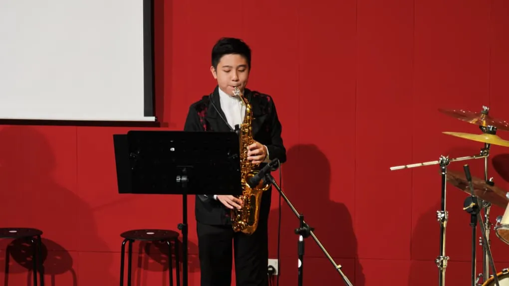 Young saxophonist playing at a music academy recital in a Theatrette