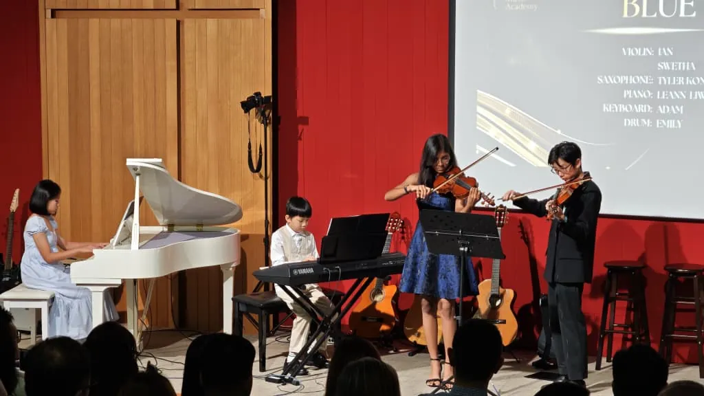Young violinists, a pianist and a keyboard player at a music academy recital in a Theatrette