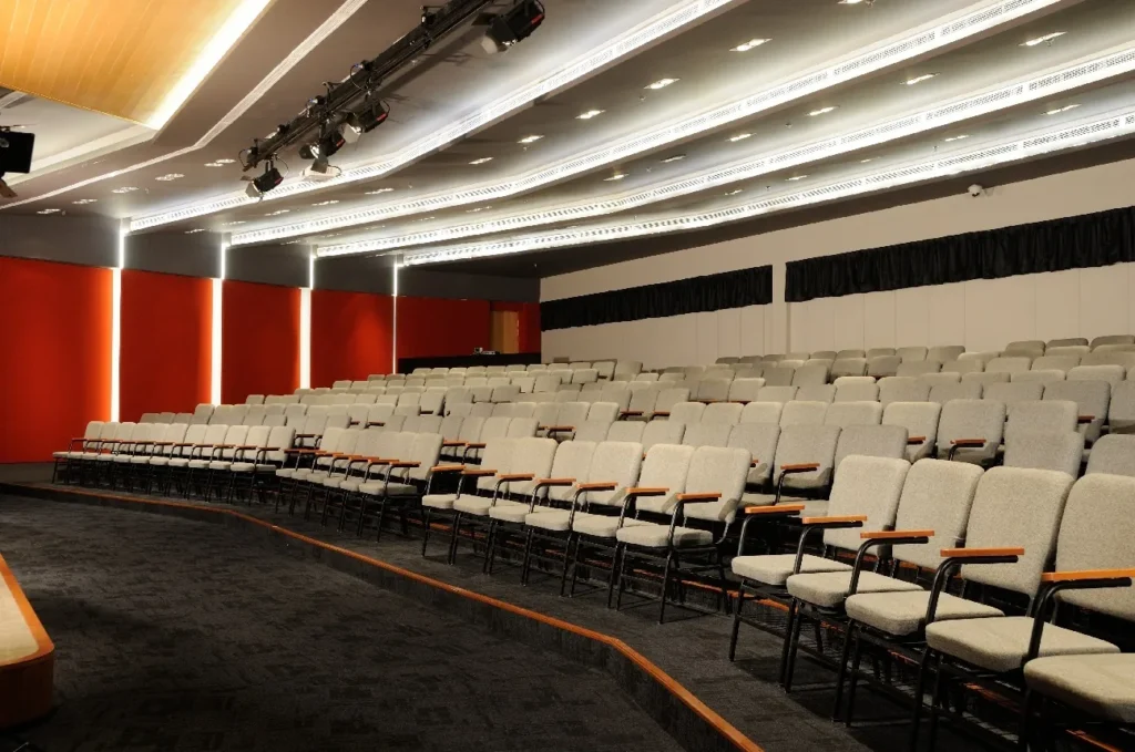 Tiered seats in a Theatrette with red walls and stage lights