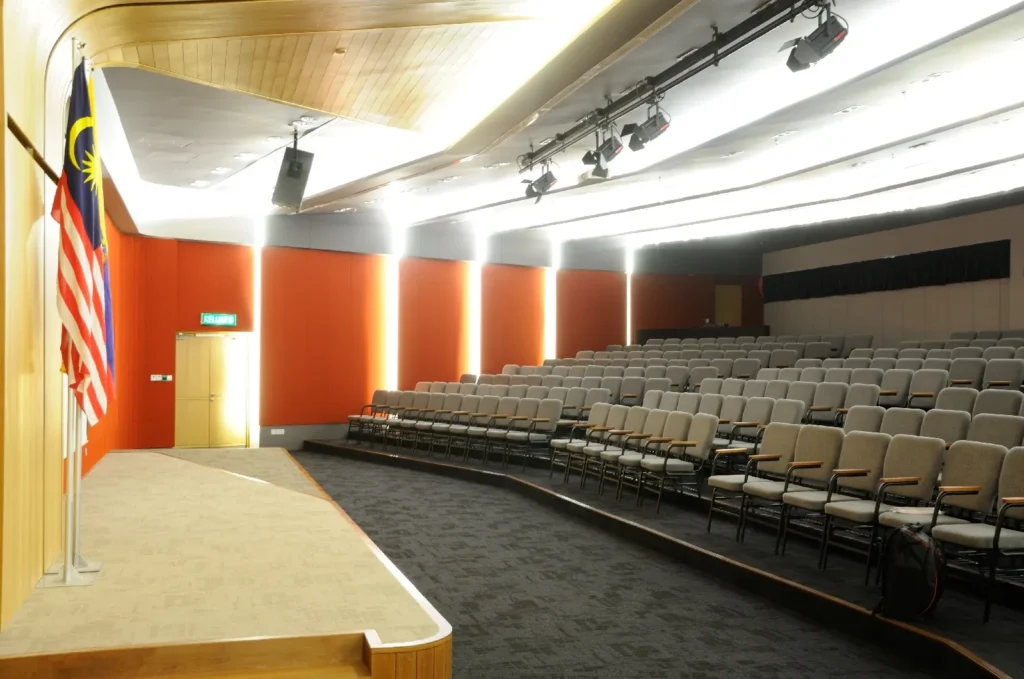 View from the edge of the stage across the tiered seats of a Theatrette with red walls